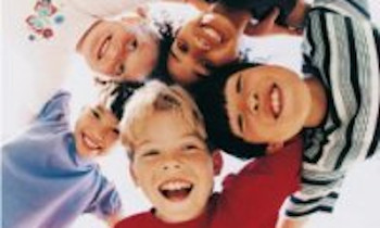 Des enfants souriant en cercle se tenant les épaules
